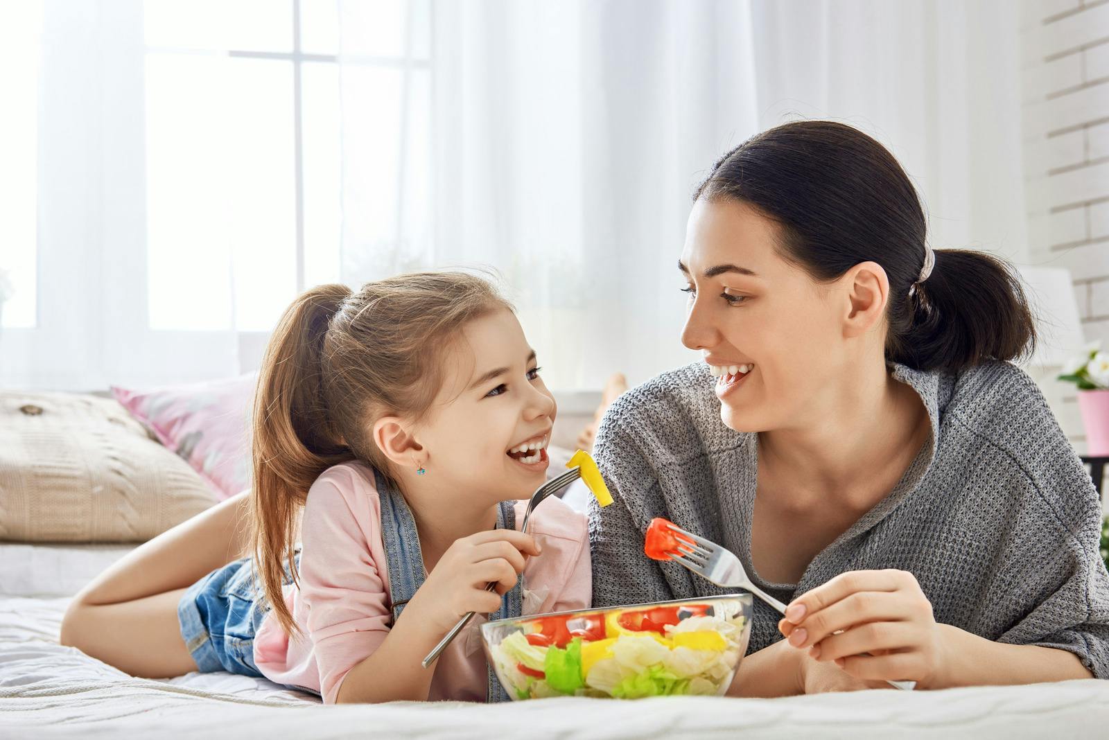 Mom and daughter laughing and eating food