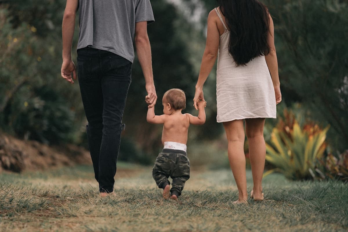 A mom and dad taking a walk with their toddler