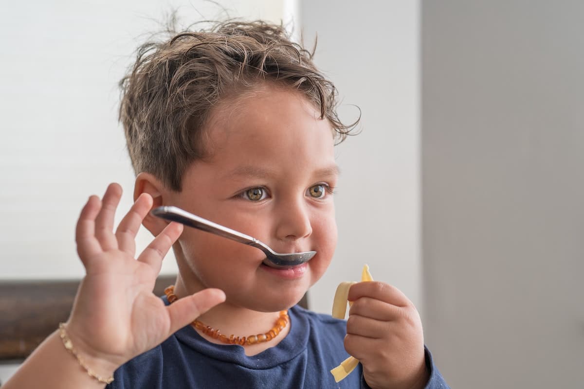 Kids eating food off of spoon